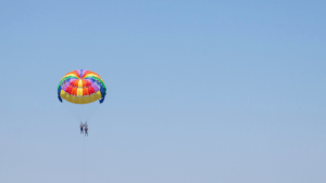 What is the difference between parasailing and paragliding at Anjuna Beach?