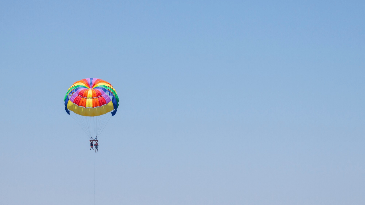 What is the difference between parasailing and paragliding at Anjuna Beach?