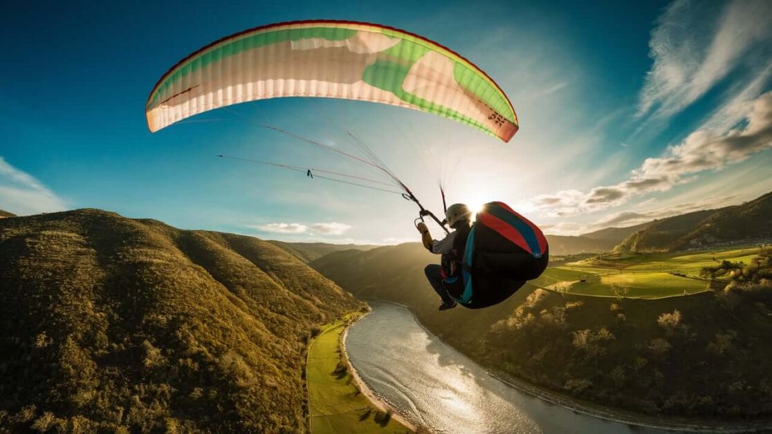 How much does parasailing cost compared to paragliding at Anjuna Beach?