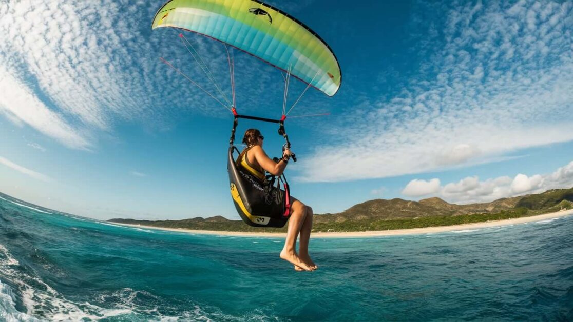 How much does parasailing cost compared to paragliding at Anjuna Beach?