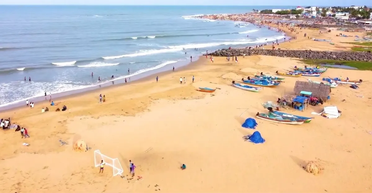 Overhead perspective of Kovalam Beach, Kerala, featuring boats and beachgoers amidst the scenic shoreline.