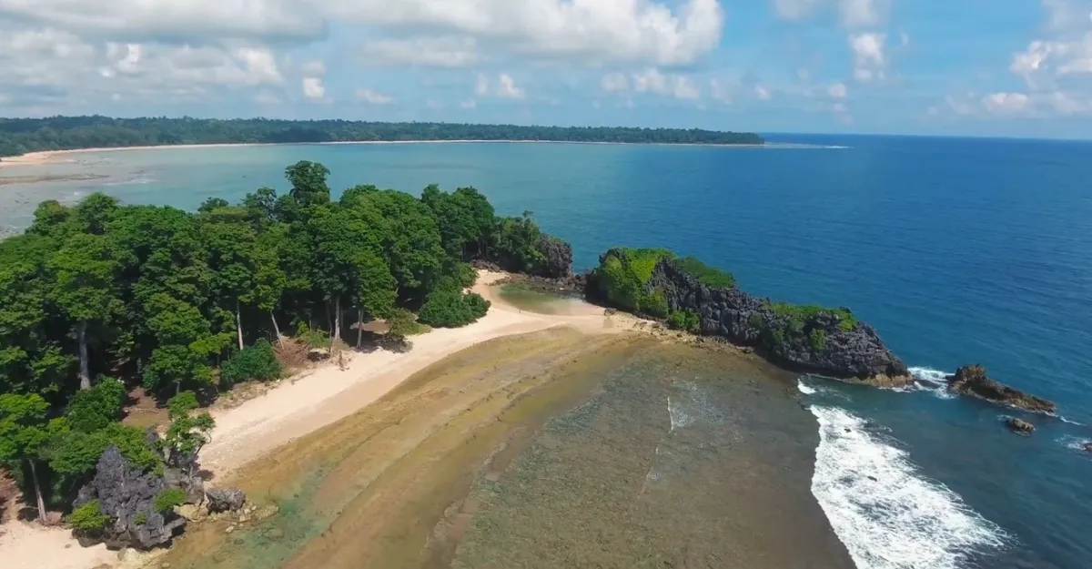 A tranquil and unspoiled view of Kalapathar Beach on Little Andaman Island, showcasing its golden sands, dense tropical forest backdrop, and a rocky outcrop meeting the azure ocean waves – an example of India’s beautiful yet lesser-known beaches. Why are beaches in India not as popular as other countries?