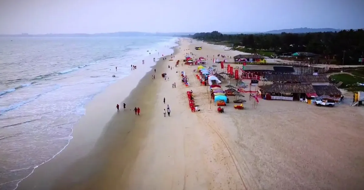 Majorda Beach in Goa, showcasing its natural beauty and serene environment with clear turquoise waters gently lapping over golden sands, under a vast blue sky, exemplifying why Goa beaches are famous for their natural beauty and environment.