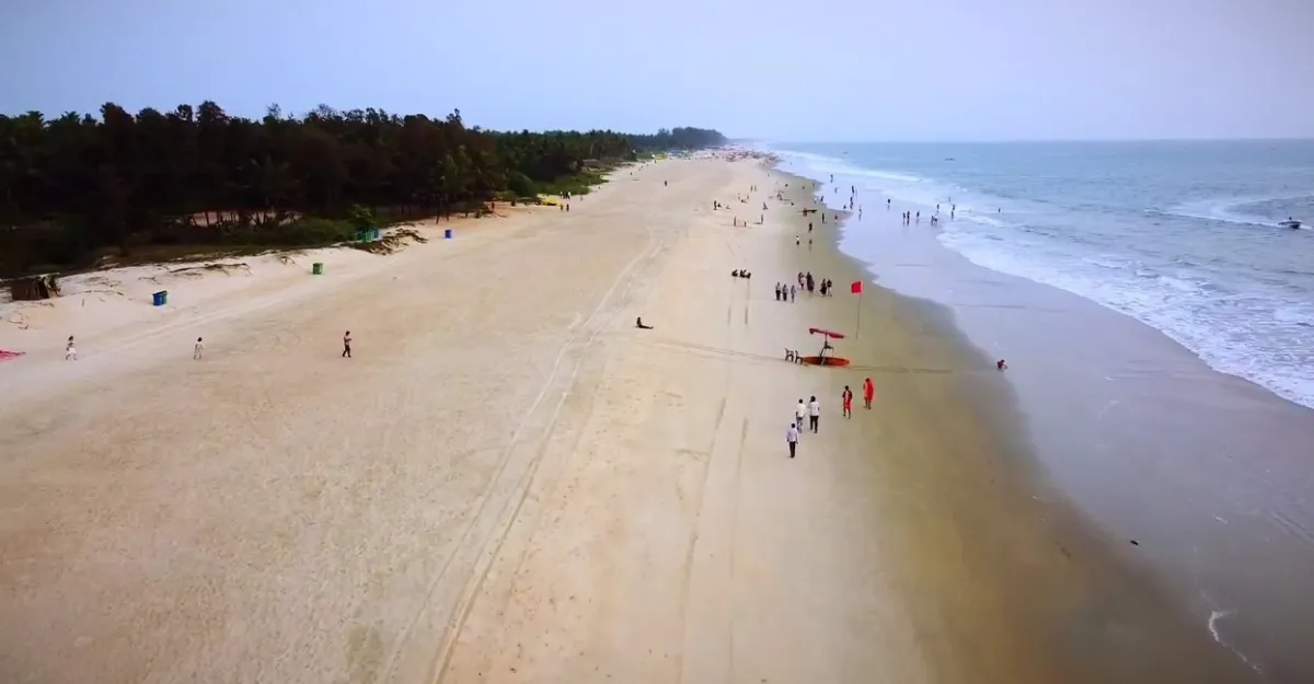 Majorda Beach in Goa, showcasing its natural beauty and serene environment with clear turquoise waters gently lapping over golden sands, under a vast blue sky, exemplifying why Goa beaches are famous for their natural beauty and environment.