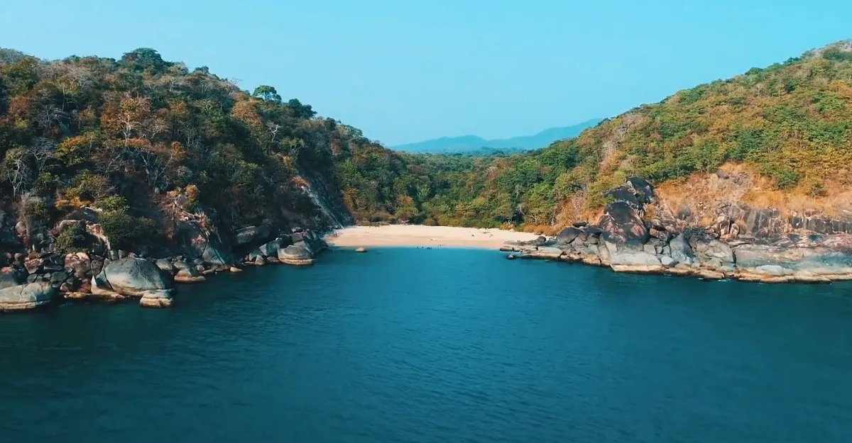 Scenic aerial view of Butterfly Beach in Goa, showcasing its secluded golden sandy cove surrounded by lush green hills and tranquil blue waters. The remote and picturesque beach, known for its butterfly-shaped bay, offers a serene getaway for nature lovers and adventure seekers. Ideal for those exploring offbeat destinations in South Goa, Butterfly Beach is accessible by boat or through scenic trekking routes. This pristine beach is famous for its stunning sunsets, dolphin sightings, and peaceful atmosphere, making it a must-visit for travelers seeking untouched beauty.